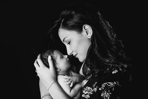 Baby Fotografin Düsseldorf: Junge Mutter hält das Näschen ihres kleinen Babys direkt vor die eigene Nase und hält das Kleine dabei zärtlich in den Händen.